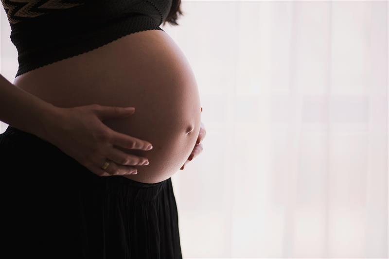  A pregnant woman dressed in black cradles her abdomen
